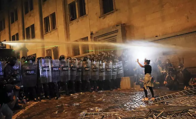 FILE A demonstrator gestures trying to stop riot police during an opposition protest against "the Russian law" near the Parliament building in Tbilisi, Georgia, on Tuesday, April 30, 2024. Thousands of people rallied in Georgia for weeks against the foreign influence bill. Critics compared it to similar legislation Russia uses to stifle dissent, and they worried it would jeopardize Georgia's prospects of joining the European Union. (AP Photo/Zurab Tsertsvadze, File)