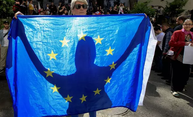 FILE A demonstrator holds a EU flag during an opposition protest against the foreign influence bill at the Parliamentary building in Tbilisi, Georgia, on May 28, 2024. Thousands of people rallied in Georgia for weeks against the foreign influence bill. Critics compared it to similar legislation Russia uses to stifle dissent, and they worried it would jeopardize Georgia's prospects of joining the European Union. (AP Photo/Shakh Aivazov, File)