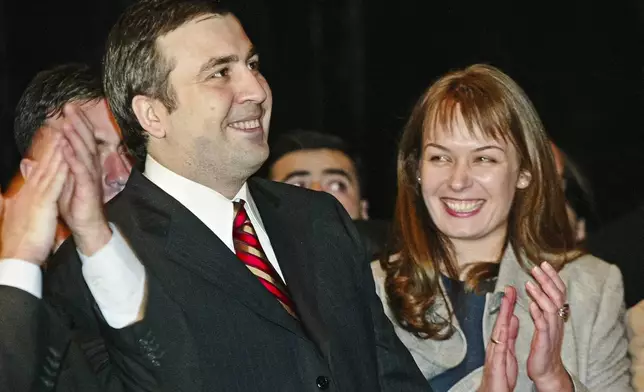 FILE Top presidential candidate Mikhail Saakashvili, left, smiles while listening to the preliminary election results as his wife Sandra Roelofs applauds him in Georgia's capital Tbilisi Sunday, Jan. 4, 2004. A pro-Western reformist, Saakashvili was president in 2004-13 and was renowned for his energetic efforts against Georgia's endemic corruption, but Georgians became increasingly uneasy with what they saw as his authoritarian inclinations and his sometimes-mercurial behavior. (AP Photo/Ivan Sekretarev, File)