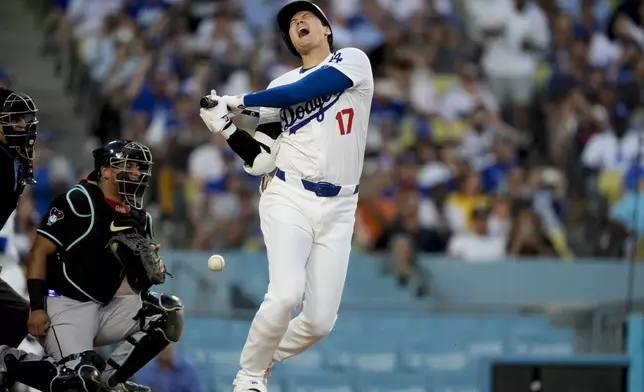 Los Angeles Dodgers designated hitter Shohei Ohtani reacts after being hit by a foul tip during the third inning of a baseball game against the Arizona Diamondbacks, Tuesday, July 2, 2024, in Los Angeles. (AP Photo/Ryan Sun)