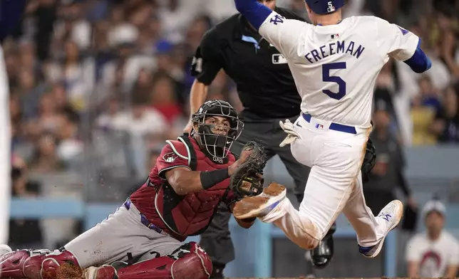 Los Angeles Dodgers' Freddie Freeman, right, attempts to score from third on the line out by Miguel Rojas before being tagged out by Arizona Diamondbacks catcher Gabriel Moreno during the third inning of a baseball game Wednesday, July 3, 2024, in Los Angeles. (AP Photo/Mark J. Terrill)