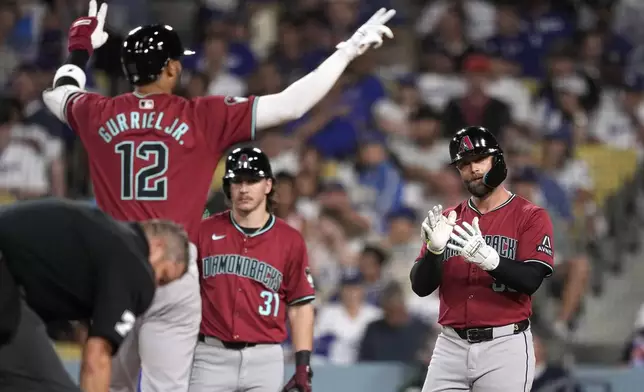 Arizona Diamondbacks' Lourdes Gurriel Jr., left, and Christian Walker, right, celebrate as Jake McCarthy watches after Gurriel Jr. hit a two-run home run during the sixth inning of a baseball game against the Los Angeles Dodgers Wednesday, July 3, 2024, in Los Angeles. (AP Photo/Mark J. Terrill)