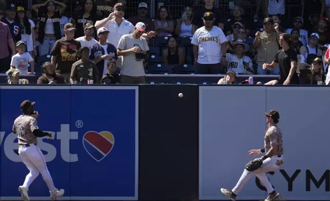 San Diego Padres left fielder Jurickson Profar, left, and center fielder Jackson Merrill, right, can't reach an RBI ground rule double by Arizona Diamondbacks' Alek Thomas before it bounces over the wall during the ninth inning of a baseball game Sunday, July 7, 2024, in San Diego. (AP Photo/Gregory Bull)