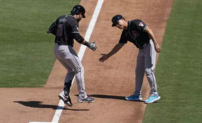 Arizona Diamondbacks' Eugenio Suarez, left, celebrates with third base coach Tony Perezchica after hitting a two-run home run during the seventh inning of a baseball game against the San Diego Padres, Sunday, July 7, 2024, in San Diego. (AP Photo/Gregory Bull)