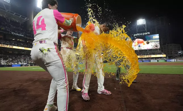 San Diego Padres' Manny Machado, right, is doused by teammates Tyler Wade, left, and Jackson Merrill after hitting a game-winning two-run home run during the ninth inning of a baseball game against the Arizona Diamondbacks, Friday, July 5, 2024, in San Diego. The Padres won, 10-8. (AP Photo/Gregory Bull)