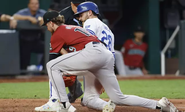 Kansas City Royals' Kyle Isbel (28) scores on a wild pitch as Arizona Diamondbacks pitcher Ryne Nelson, left, is late with the tag during the fourth inning of a baseball game in Kansas City, Mo., Wednesday, July 24, 2024. (AP Photo/Colin E. Braley)