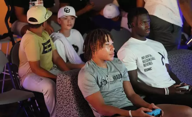 Fans look on as Colorado wide receiver Kaleb Mathis, front left, faces off against running back Kam Mikell, right, during the EA Sports College Football 25 video game release party Friday, July 19, 2024, at the Memorial Union on the campus of the University of Colorado in Boulder, Colo. (AP Photo/David Zalubowski)