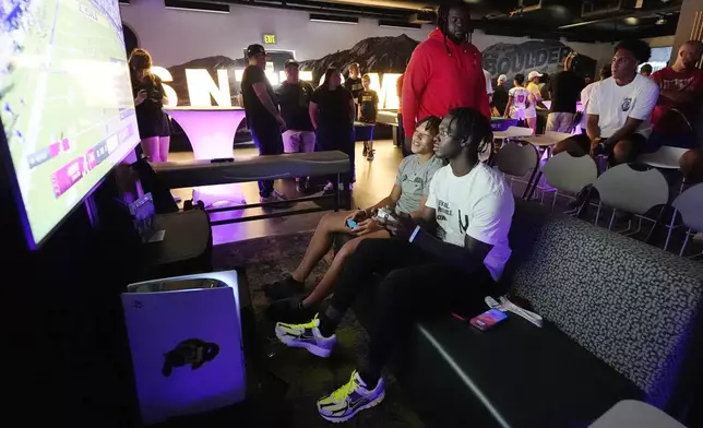 Colorado running back Kam Mikell, front right, and wide receiver Kaleb Mathis, front left, face off during the EA Sports College Football 25 video game release party Friday, July 19, 2024, at the Memorial Union on the campus of the University of Colorado in Boulder, Colo.(AP Photo/David Zalubowski)