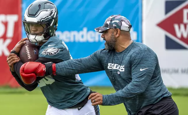 Philadelphia Eagles running back Saquon Barkley, left, runs a drill against running backs coach Jemal Singleton, right, stretches during practice at NFL football training camp, Wednesday, July 24, 2024, in Philadelphia. (AP Photo/Chris Szagola)