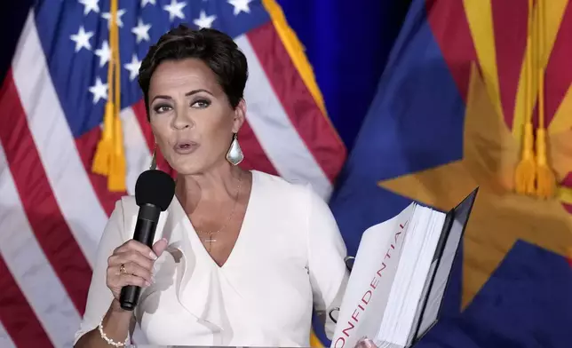 Republican Arizona Senate candidate Kari Lake holds up a binder of Democratic Rep. Ruben Gallego's voting record, Lake's opponent in the upcoming general election, while speaking after being declared the primary winner Tuesday, July 30, 2024, in Phoenix. (AP Photo/Ross D. Franklin)