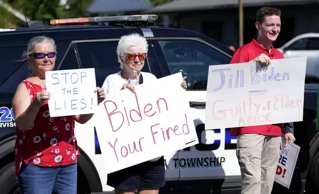 Protesters carry signs in Harrisburg, Pa., as President Joe Biden attends a campaign event Sunday, July 7, 2024. (AP Photo/Stephanie Scarbrough)