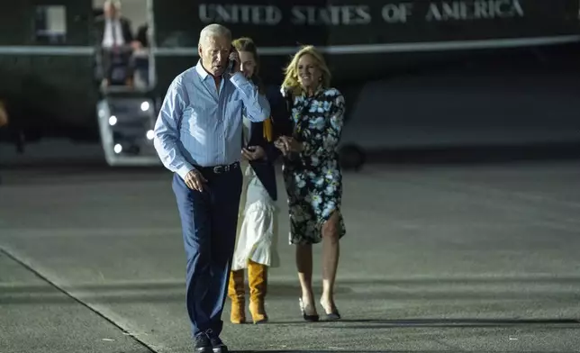 President Joe Biden, left, talks on the phone as he walks to board Air Force One at McGuire Air Force Base, Saturday, June 29, 2024, in Burlington County, N.J. (AP Photo/Evan Vucci)