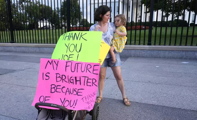 Anna Filipic, of Washington, holds her daughter Louisa Monje, 2, outside the White House in Washington, Sunday, July 21, 2024, as they show support for President Joe Biden. Biden dropped out of the 2024 race for the White House on Sunday, ending his bid for reelection following a disastrous debate with Donald Trump that raised doubts about his fitness for office just four months before the election. (AP Photo/Susan Walsh)