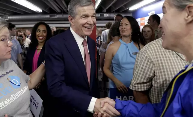 North Carolina Governor Roy Cooper, center, smiles as he talks with with supporters at a press conference, Thursday, July 25, 2024, in Raleigh, N.C. Cooper is one of the people being considered to be likely Democratic presidential candidate Vice President Kamala Harris' running mate. (AP Photo/Chris Seward)