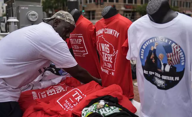 A vendor sorts his merchandise is seen during the second day of the 2024 Republican National Convention near the Fiserv Forum, Tuesday, July 16, 2024, in Milwaukee. (AP Photo/Jae C. Hong)