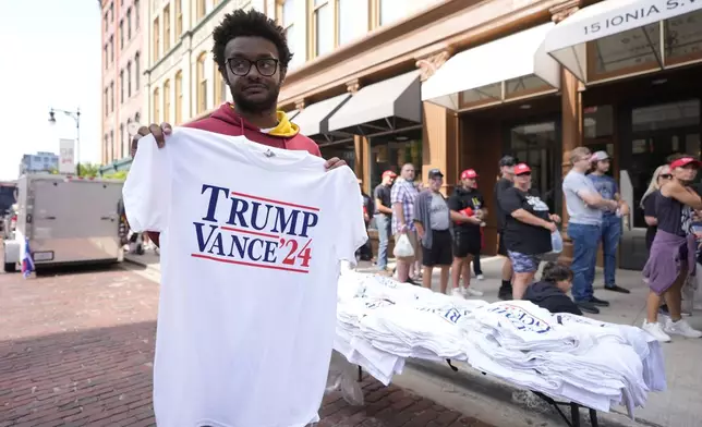 A person sells merchandise before Republican presidential candidate former President Donald Trump and Republican vice presidential candidate Sen. JD Vance, R-Ohio, speak at a campaign event, Saturday, July 20, 2024, at Van Andel Arena in Grand Rapids, Mich. (AP Photo/Carlos Osorio)