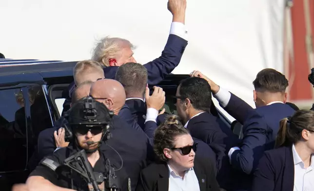 Republican presidential candidate former President Donald Trump is helped off the stage at a campaign event in Butler, Pa., on Saturday, July 13, 2024. (AP Photo/Gene J. Puskar)