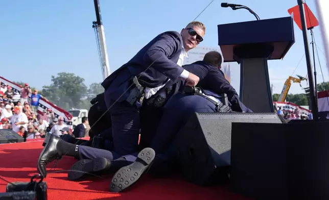 Republican presidential candidate former President Donald Trump is covered by U.S. Secret Service agents at a campaign rally, Saturday, July 13, 2024, in Butler, Pa. (AP Photo/Evan Vucci)