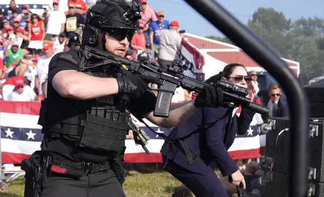 U.S. Secret Service agents surround the stage as other agents cover Republican presidential candidate former President Donald Trump at a campaign rally, Saturday, July 13, 2024, in Butler, Pa. (AP Photo/Evan Vucci)