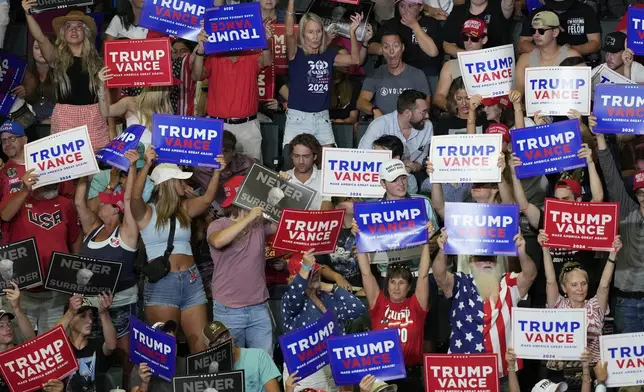 Supporters of Republican presidential candidate former President Donald Trump and Republican vice presidential candidate Sen. JD Vance, R-Ohio, hold signs in the audience at a campaign event, Saturday, July 20, 2024, at Van Andel Arena in Grand Rapids, Mich. (AP Photo/Carlos Osorio)