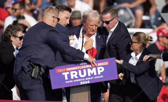 Republican presidential candidate former President Donald Trump is helped off the stage at a campaign event in Butler, Pa., Saturday, July 13, 2024. (AP Photo/Gene J. Puskar)