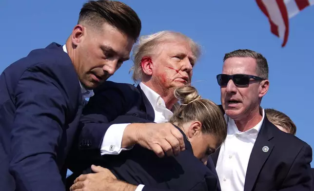 Republican presidential candidate former President Donald Trump gestures as he is surrounded by U.S. Secret Service agents at a campaign rally, Saturday, July 13, 2024, in Butler, Pa. (AP Photo/Evan Vucci)