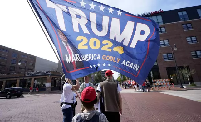 Supporters of Republican presidential candidate former President Donald Trump and Republican vice presidential candidate Sen. JD Vance, R-Ohio, carry a sign before a campaign event, Saturday, July 20, 2024, at Van Andel Arena in Grand Rapids, Mich. (AP Photo/Carlos Osorio)