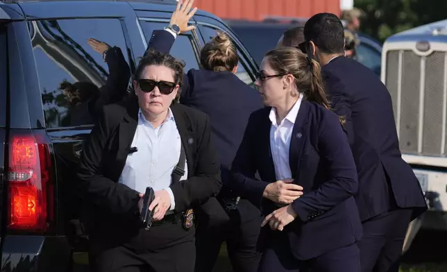 FILE - U.S. Secret Service agents surround the vehicle carrying Republican presidential candidate former President Donald Trump at a campaign rally, Saturday, July 13, 2024, in Butler, Pa. (AP Photo/Evan Vucci, File)
