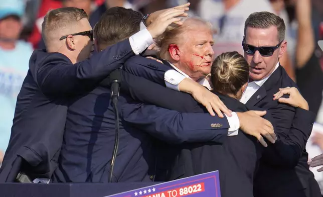FILE - Republican presidential candidate former President Donald Trump is surrounded by U.S. Secret Service agents as he is helped off the stage at a campaign rally in Butler, Pa., Saturday, July 13, 2024. (AP Photo/Gene J. Puskar, File)