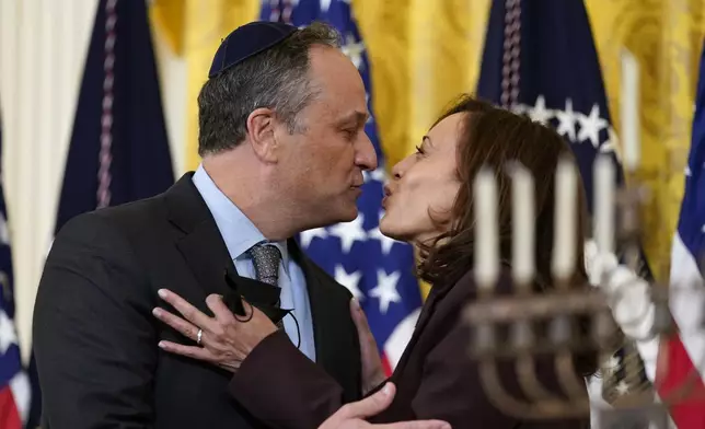 FILE - Vice President Kamala Harris and second gentleman Doug Emhoff kiss during an event in the East Room of the White House in Washington, to light the menorah to celebrate Hanukkah, Dec. 1, 2021. Republican presidential candidate former President Donald Trump in an interview on Tuesday claimed Vice President Kamala Harris “doesn’t like Jewish people,” despite being married to a Jewish man and Trump seemed to agree with a radio host who called second gentleman Doug Emhoff “a crappy Jew.” (AP Photo/Susan Walsh, File)