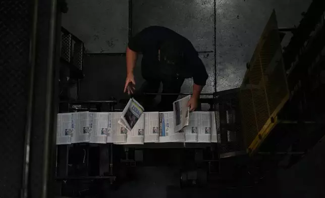 Kurt Slater, pressman at the Butler Eagle newspaper, pulls papers as they come off the press, Thursday, July 18, 2024, in Butler, Pa. (AP Photo/Matt Slocum)