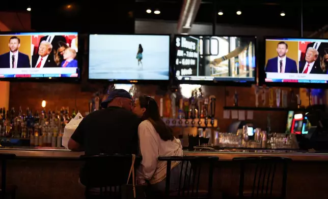 A couple kisses at 11th Frame Bar and Grille in Butler, Pa., as the Republican National Convention broadcasts, Thursday, July 18, 2024. (AP Photo/Matt Slocum)