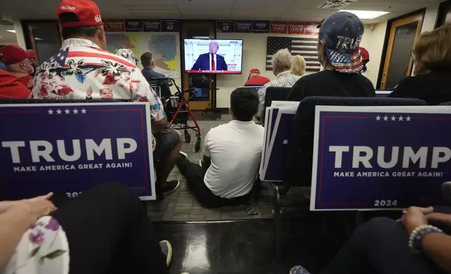 Supporters of Republican presidential candidate former President Donald Trump watch his speech at the Republican National Convention on a television from the Arizona GOP headquarters Thursday, July 18, 2024, in Phoenix. (AP Photo/Ross D. Franklin)