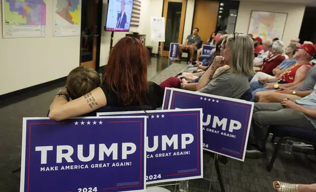 Supporters of Republican presidential candidate former President Donald Trump watch his speech at the Republican National Convention in Milwaukee on a television at the Arizona GOP headquarters Thursday, July 18, 2024, in Phoenix. (AP Photo/Ross D. Franklin)