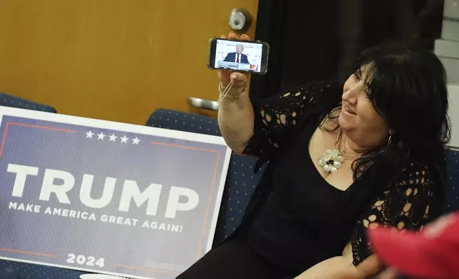 A supporter of Republican presidential candidate former President Donald Trump watches his speech at the Republican National Convention on a cellphone at the Arizona GOP headquarters Thursday, July 18, 2024, in Phoenix. (AP Photo/Ross D. Franklin)