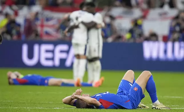 Slovakia players lie on the pitch after a round of sixteen match between England and Slovakia at the Euro 2024 soccer tournament in Gelsenkirchen, Germany, Sunday, June 30, 2024. (AP Photo/Matthias Schrader)