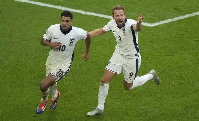 England's Jude Bellingham, left, celebrates with Harry Kane after scoring his side's first goal during a round of sixteen match between England and Slovakia at the Euro 2024 soccer tournament in Gelsenkirchen, Germany, Sunday, June 30, 2024. (AP Photo/Ebrahim Noroozi)