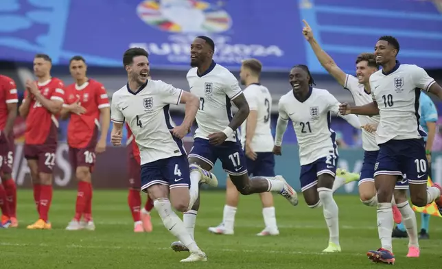 England players celebrate after Trent Alexander-Arnold scored the winning goal during the penalty shootout of a quarterfinal match between England and Switzerland at the Euro 2024 soccer tournament in Duesseldorf, Germany, Saturday, July 6, 2024. (AP Photo/Martin Meissner)