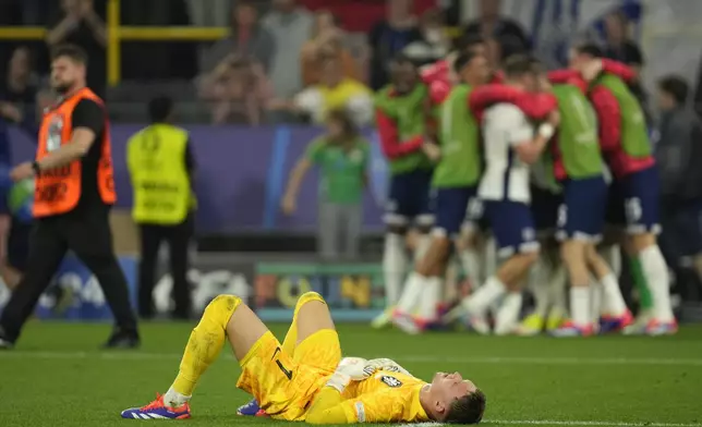 Netherlands goalkeeper Bart Verbruggen lies on the pitch as England players celebrate after a semifinal match between the Netherlands and England at the Euro 2024 soccer tournament in Dortmund, Germany, Wednesday, July 10, 2024. (AP Photo/Darko Vojinovic)