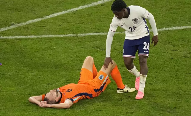 England's Kobbie Mainoo tries to comfort Stefan de Vrij of the Netherlands who is dejected after a semifinal match between the Netherlands and England at the Euro 2024 soccer tournament in Dortmund, Germany, Wednesday, July 10, 2024. (AP Photo/Andreea Alexandru)