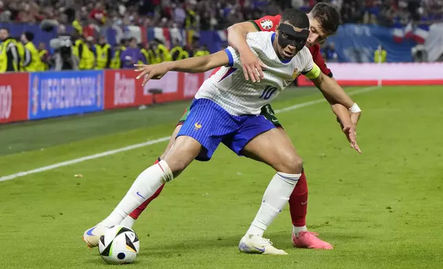 Kylian Mbappe of France, foreground, and Portugal's Ruben Dias fight for the ball during a quarter final match at the Euro 2024 soccer tournament in Hamburg, Germany, Friday, July 5, 2024. (AP Photo/Hassan Ammar)