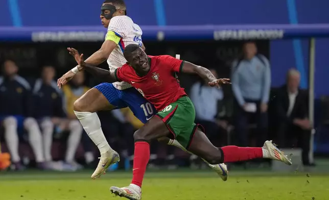 Kylian Mbappe of France challenges for the ball with Portugal's Nuno Mendes during a quarter final match between Portugal and France at the Euro 2024 soccer tournament in Hamburg, Germany, Friday, July 5, 2024. (AP Photo/Andreea Alexandru)