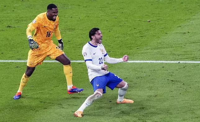 France's Theo Hernandez, right, celebrates with goalkeeper Mike Maignan after scoring the winning goal in shootout to defeat Portugal during a quarter final match at the Euro 2024 soccer tournament in Hamburg, Germany, Friday, July 5, 2024. (Marcus Brandt/dpa via AP)