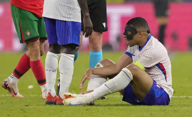 Kylian Mbappe of France sits on the pitch after an injury during a quarter final match between Portugal and France at the Euro 2024 soccer tournament in Hamburg, Germany, Friday, July 5, 2024. (AP Photo/Andreea Alexandru)