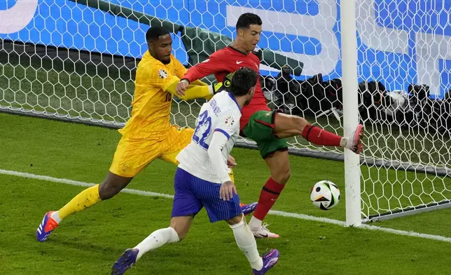 Portugal's Cristiano Ronaldo, center, is challenged by France goalkeeper Mike Maignan and Theo Hernandez of France during a quarter final match between Portugal and France at the Euro 2024 soccer tournament in Hamburg, Germany, Friday, July 5, 2024. (AP Photo/Darko Vojinovic)