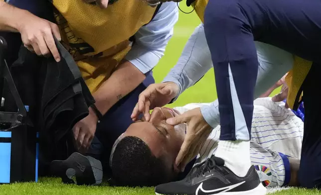 Kylian Mbappe of France is checked out for an injury during a quarter final match between Portugal and France at the Euro 2024 soccer tournament in Hamburg, Germany, Friday, July 5, 2024. (AP Photo/Frank Augstein)