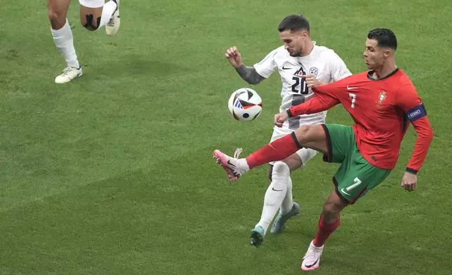 Portugal's Cristiano Ronaldo, right, controls the ball by Slovenia's Petar Stojanovic during a round of sixteen match between Portugal and Slovenia at the Euro 2024 soccer tournament in Frankfurt, Germany, Monday, July 1, 2024. (AP Photo/{Michael Probst)