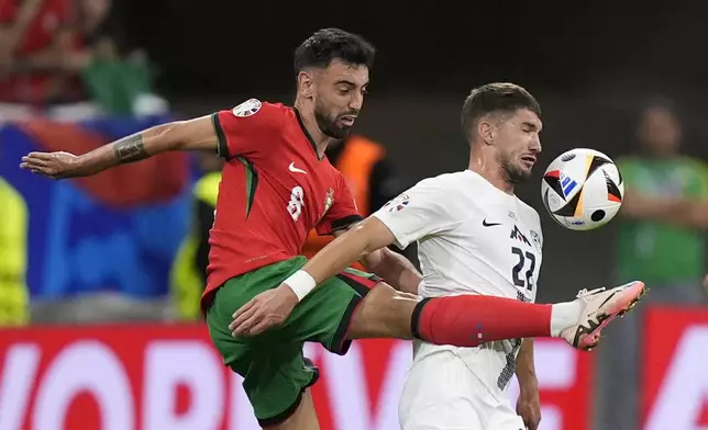 Portugal's Bruno Fernandes, left, and Slovenia's Adam Gnezda Cerin fight for the ball during a round of sixteen match between Portugal and Slovenia at the Euro 2024 soccer tournament in Frankfurt, Germany, Monday, July 1, 2024. (AP Photo/Matthias Schrader)