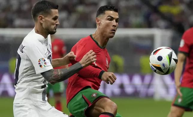 Slovenia's Petar Stojanovic, left, tries to stop Portugal's Cristiano Ronaldo during a round of sixteen match between Portugal and Slovenia at the Euro 2024 soccer tournament in Frankfurt, Germany, Monday, July 1, 2024. (AP Photo/Matthias Schrader)