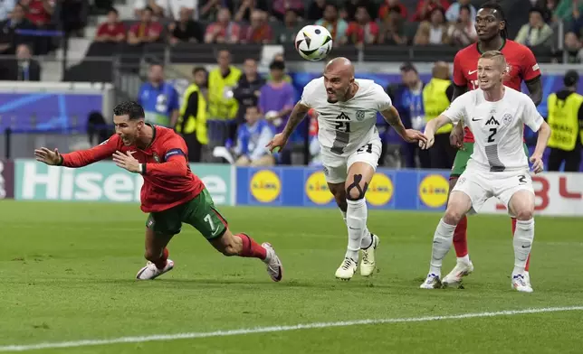 Slovenia's Vanja Drkusic, center, heads the ball as in action with Portugal's Cristiano Ronaldo, left, during a round of sixteen match between Portugal and Slovenia at the Euro 2024 soccer tournament in Frankfurt, Germany, Monday, July 1, 2024. (AP Photo/Ariel Schalit)